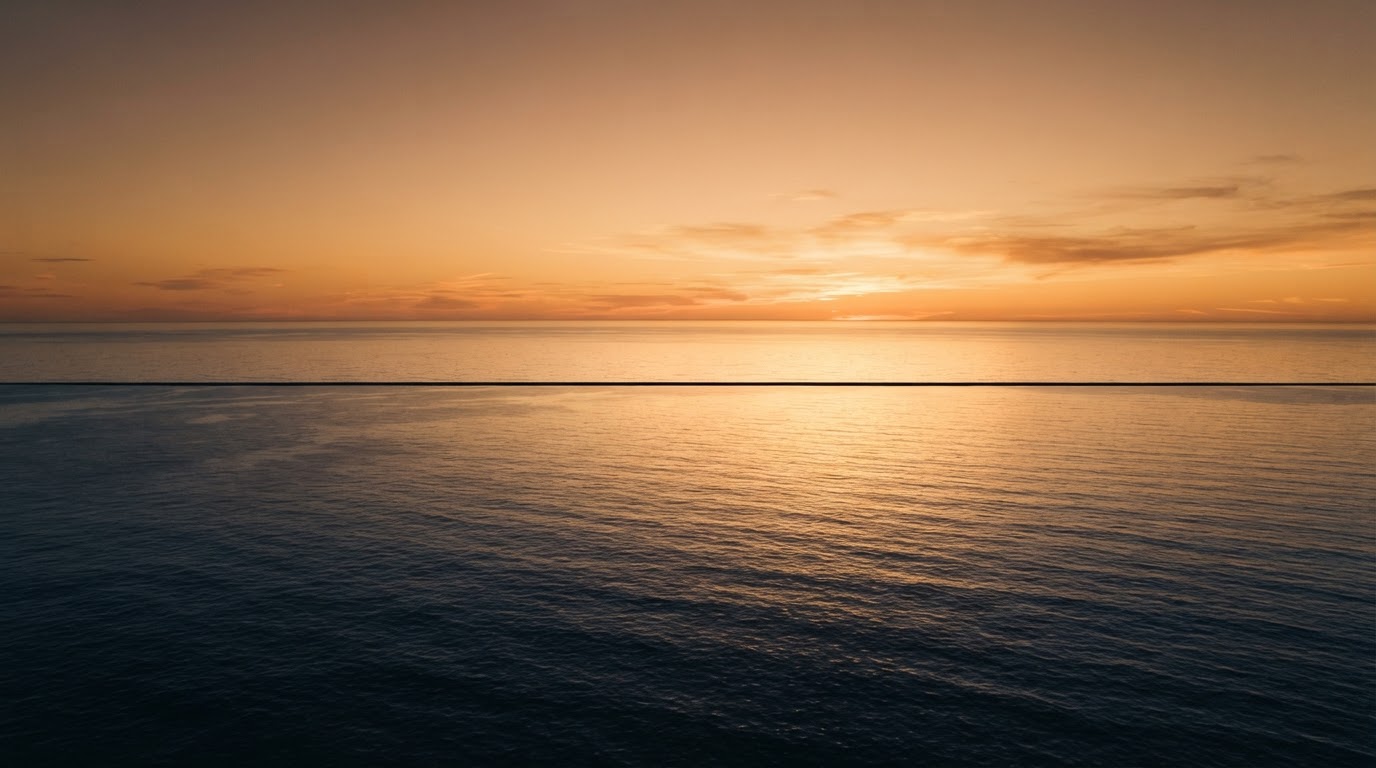 Vast calm ocean at dawn with golden light on the horizon
