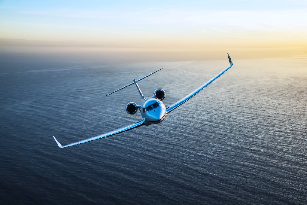 Luxury private jet flying above clouds at sunset