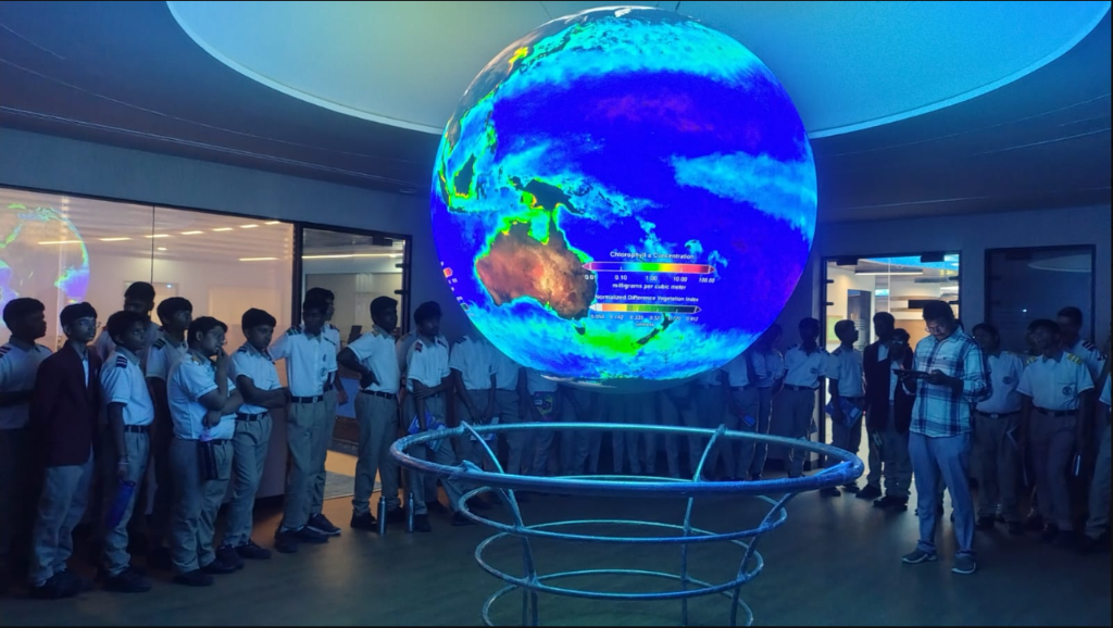 Students observing a glowing Earth globe display at a science center