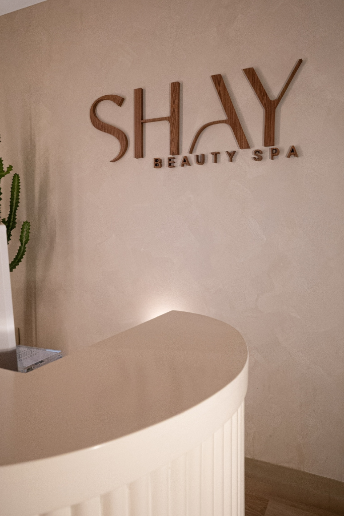 Shay Beauty Spa reception area with curved desk and wooden signage