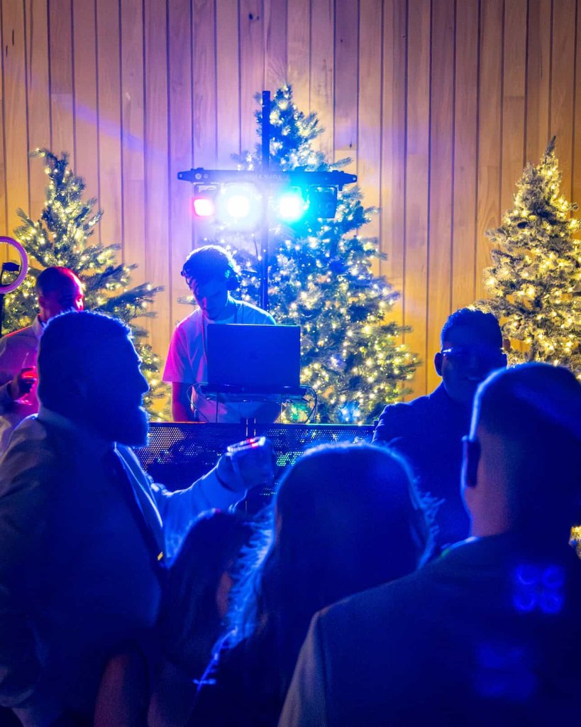Taylor McLean DJing at a holiday event with Christmas trees and stage lighting