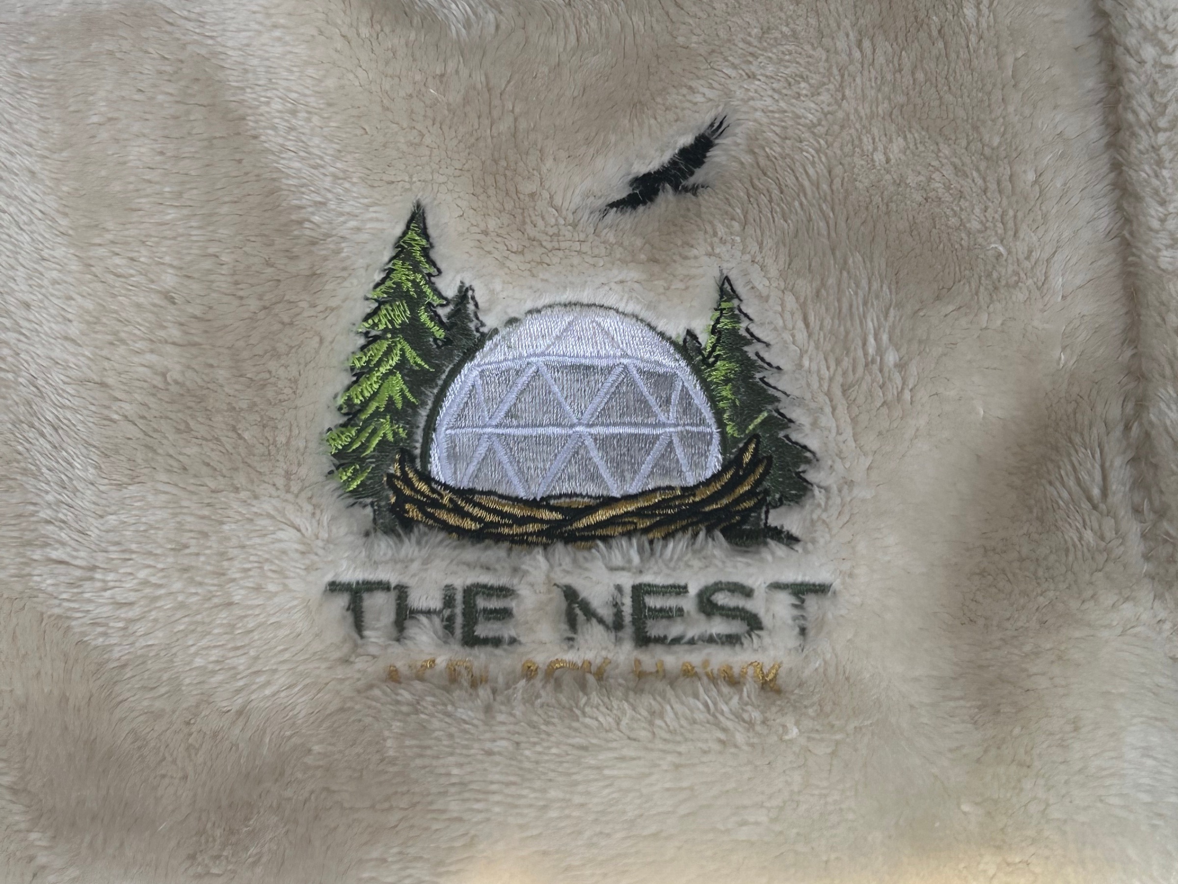 Embroidered The Nest logo detail on bedding