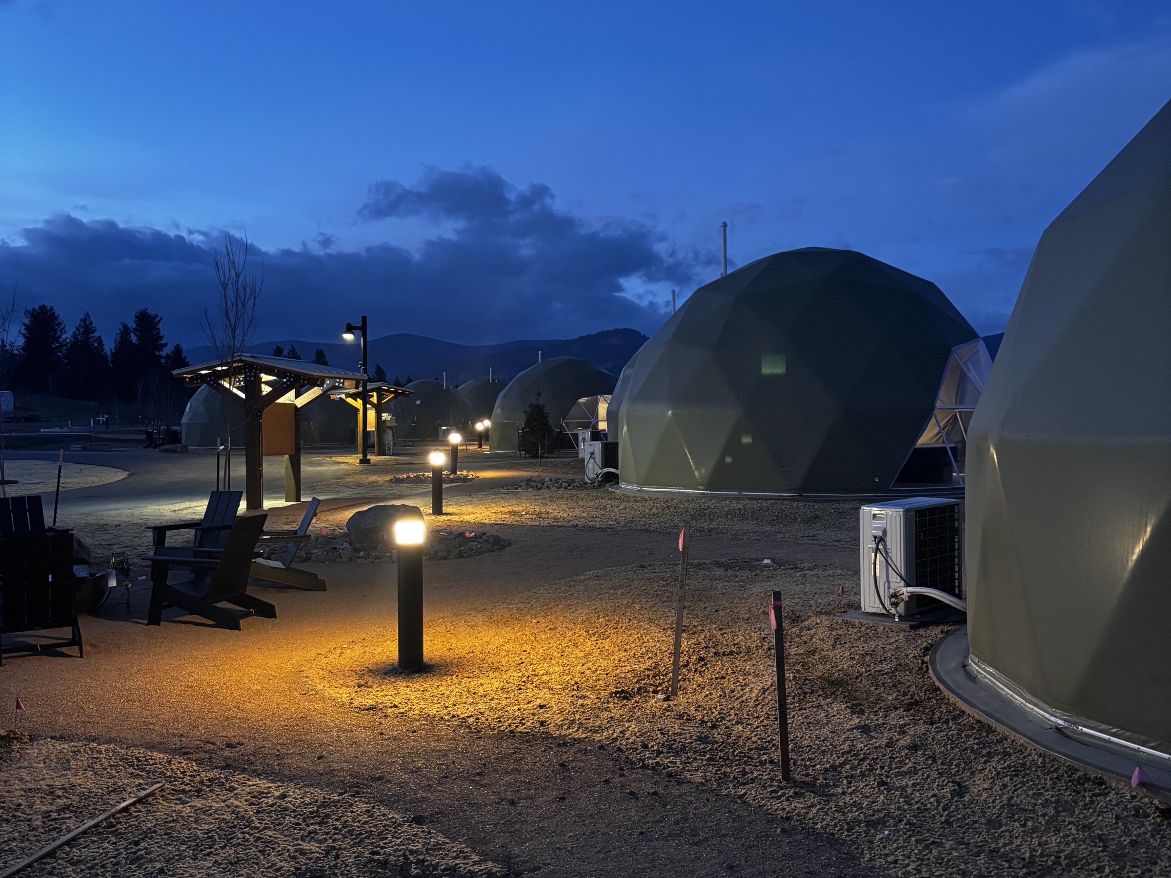Domes lit by landscape lights at dusk at The Nest