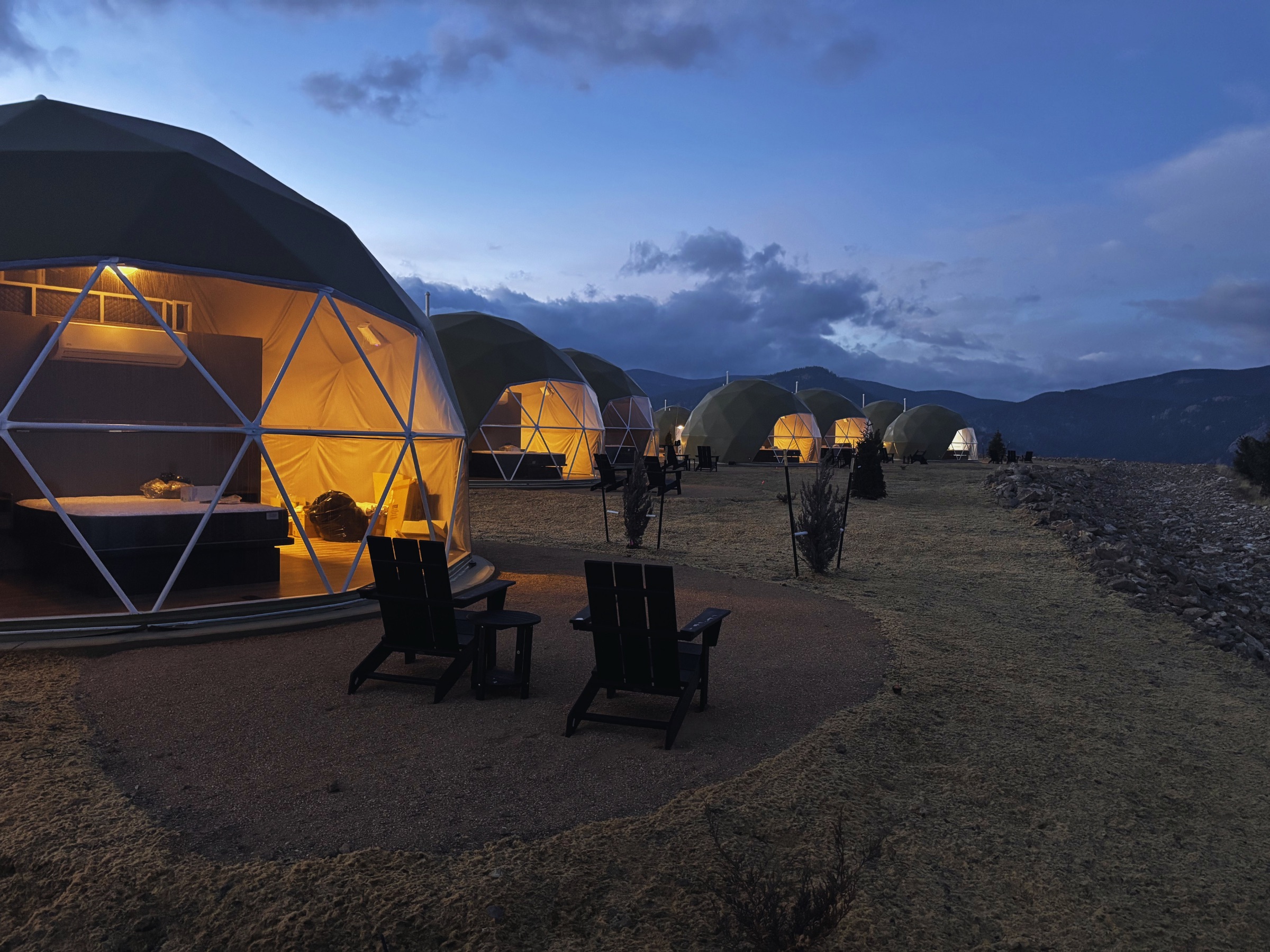 Row of geodesic domes glowing at twilight at The Nest