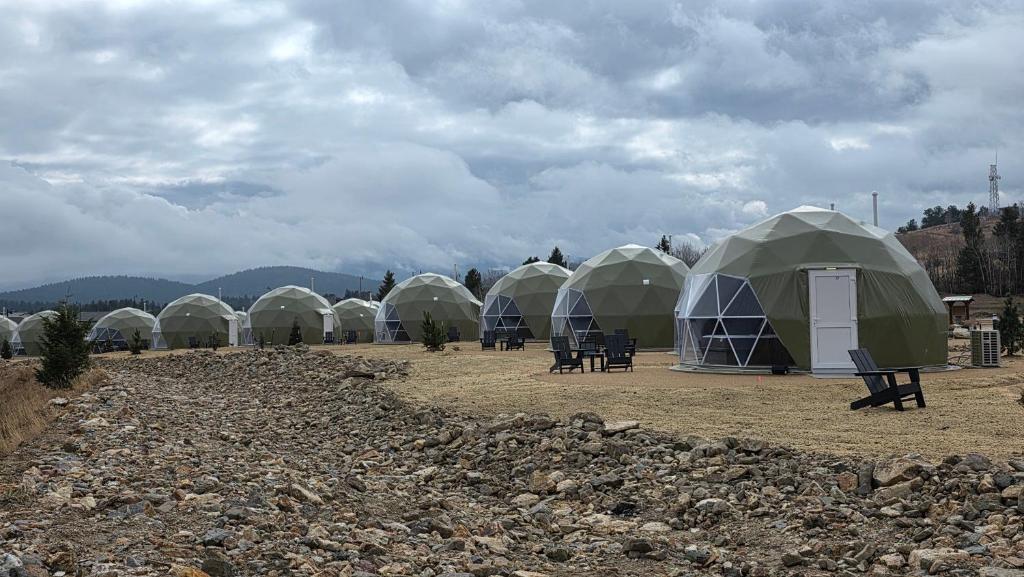 Row of geodesic domes under a cloudy mountain sky
