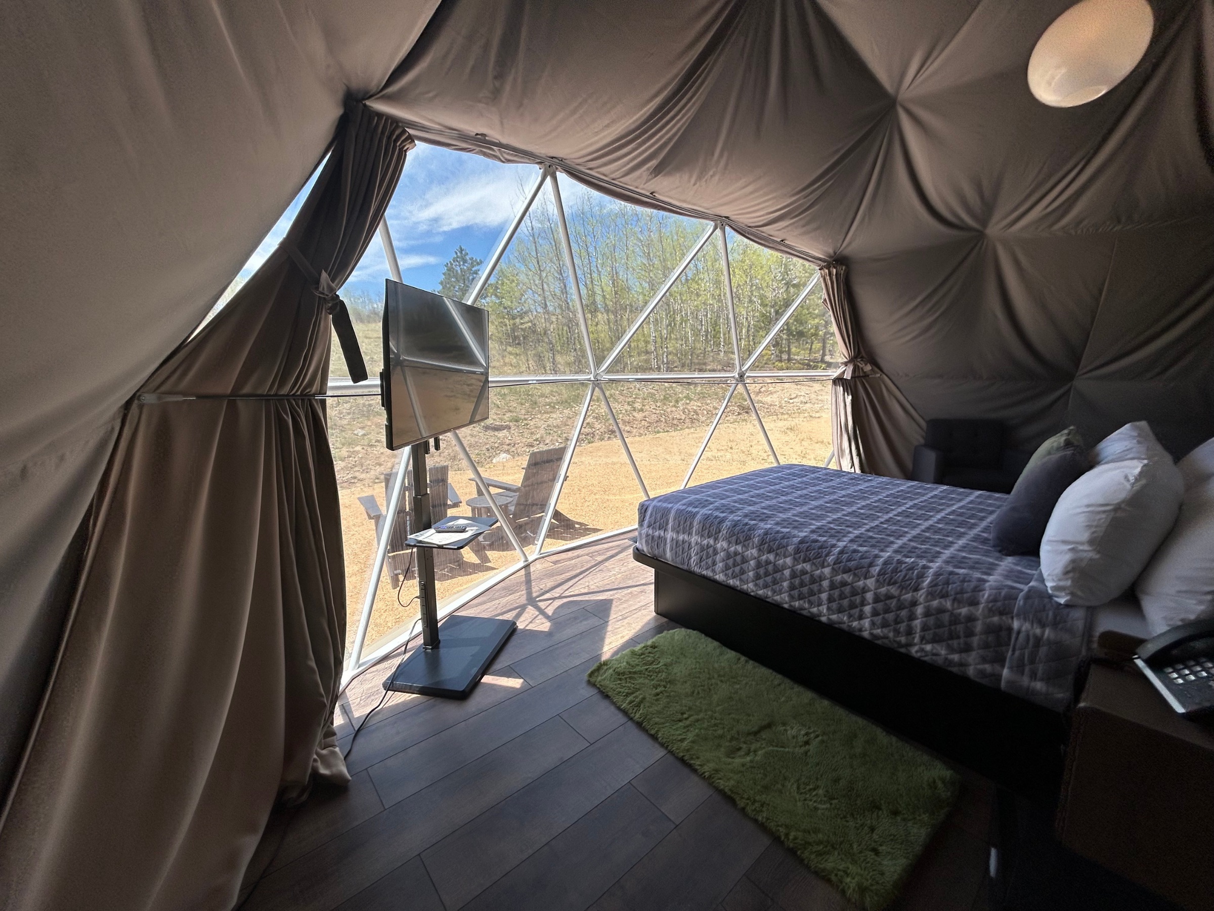 Bed and TV inside a dome with mountain view