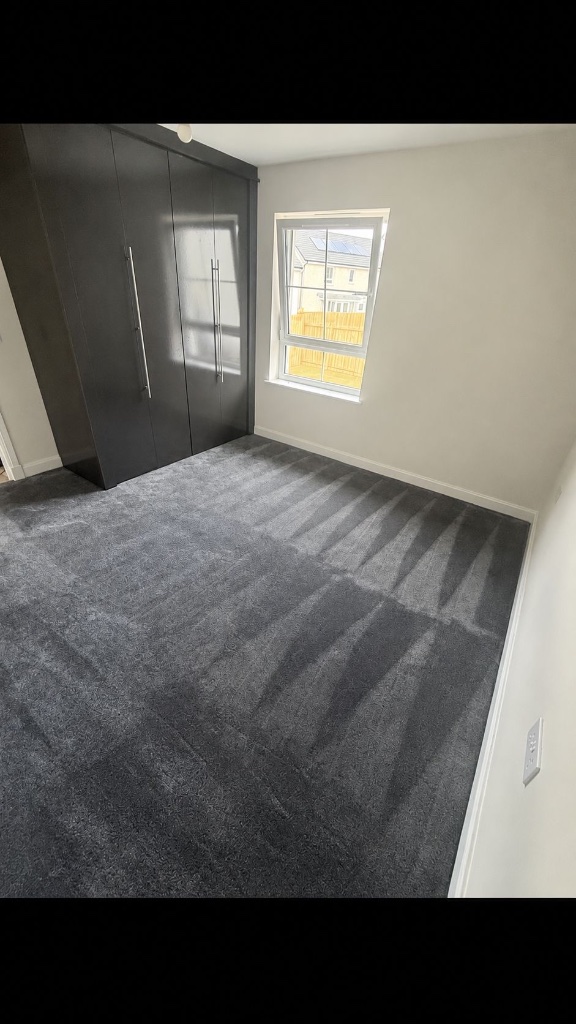 Freshly fitted plush dark grey carpet in a bedroom with clean vacuum lines