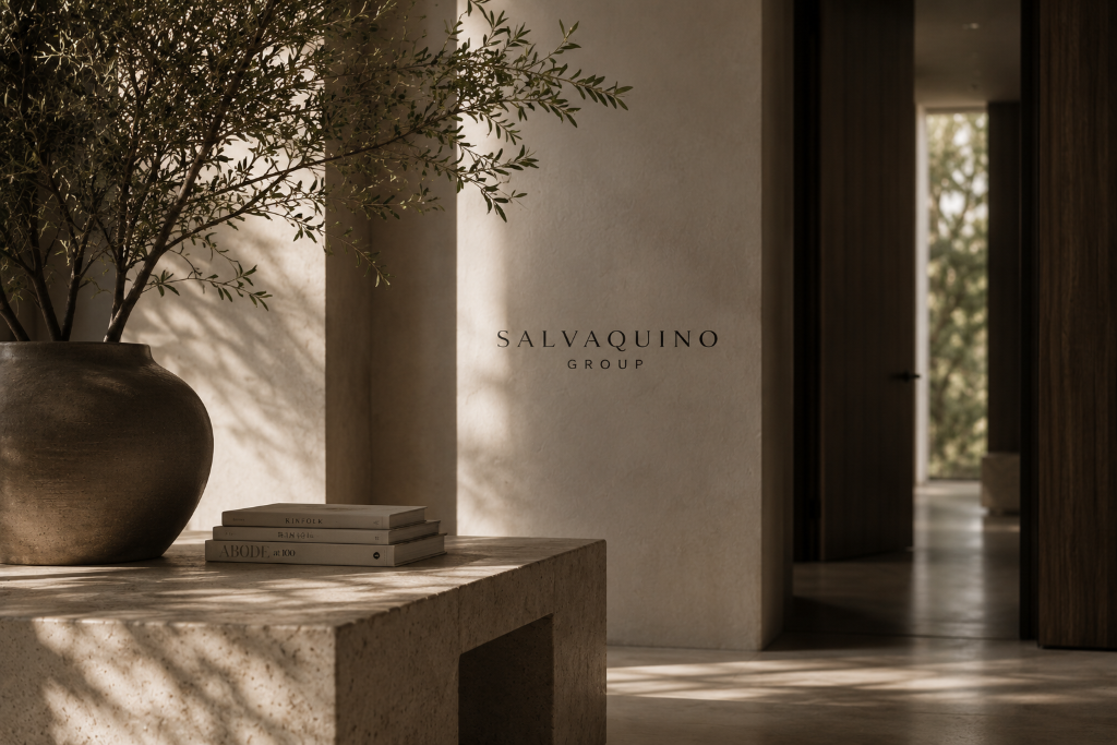 Minimalist interior with stone table, ceramic vase, and Salvaquino Group branding on a plaster wall