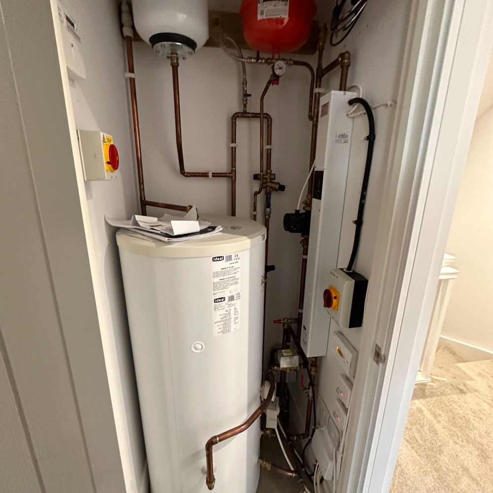 Utility cupboard with hot water cylinder and controls.