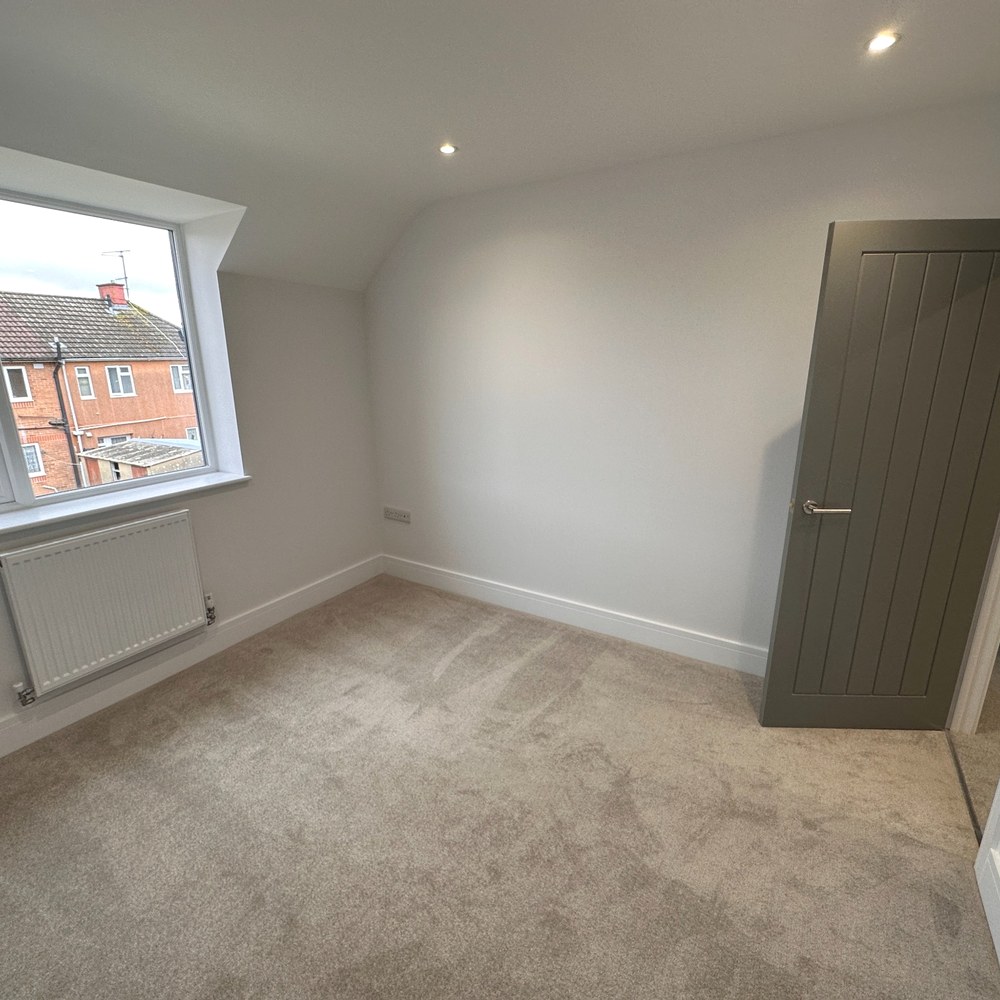 Bedroom with sloped walls and recessed lighting.