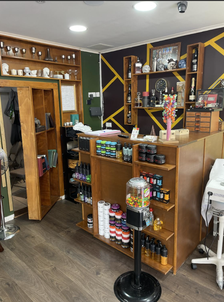 Reception desk and product shelving area at VIP Cut Barber with forest green accent wall