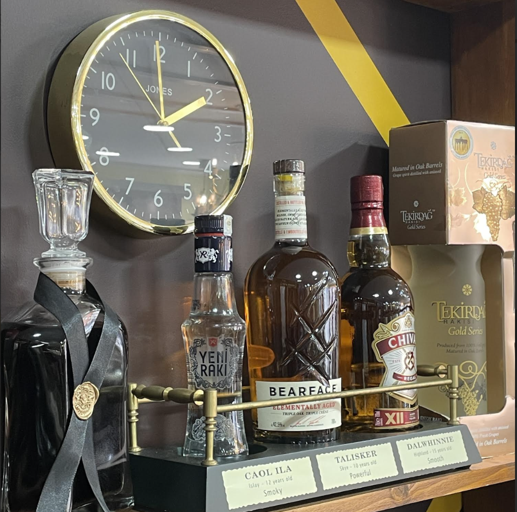 Premium drinks shelf with whiskey collection and gold-trim clock at VIP Cut Barber lounge