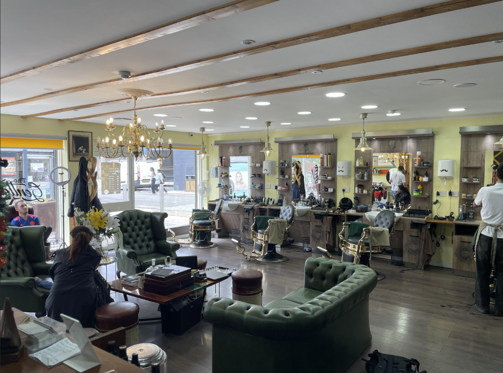 VIP Cut Barber lounge area with green leather club chairs, sofa and brass chandelier in Newton Mearns
