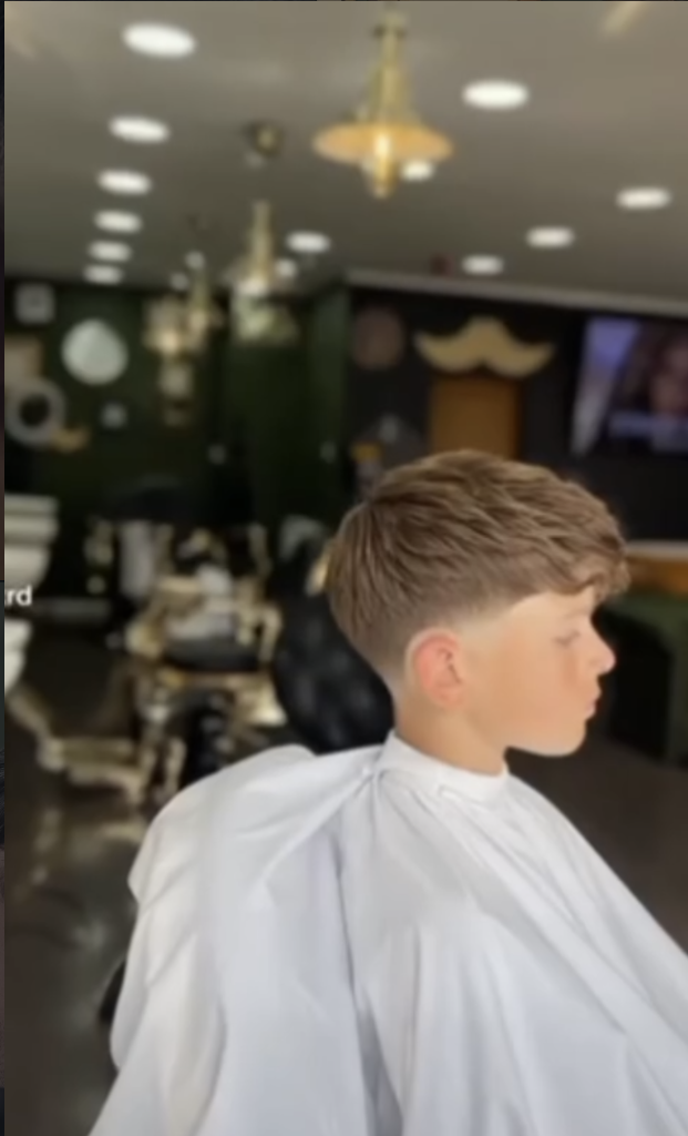 Young boy receiving a professional fade haircut in a white barber cape at VIP Cut Barber Newton Mearns
