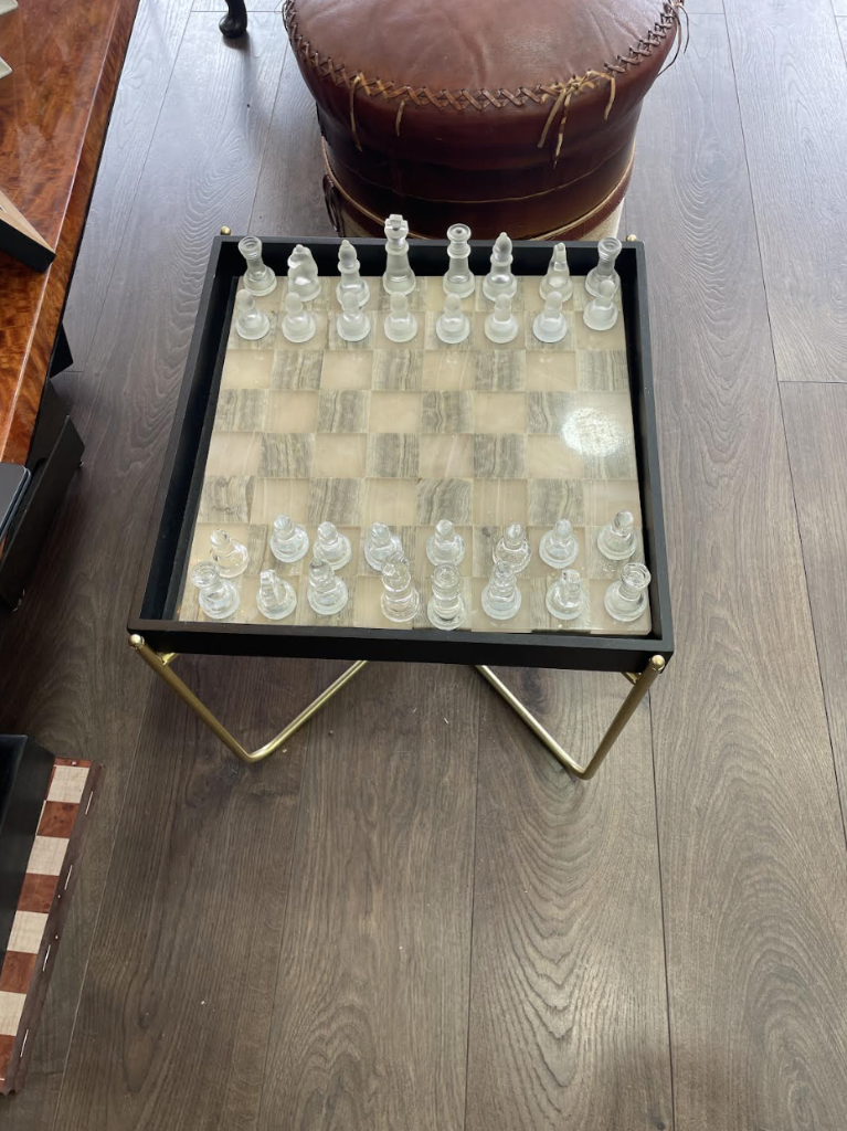 Decorative glass chess set on the dark wood floor at VIP Cut Barber