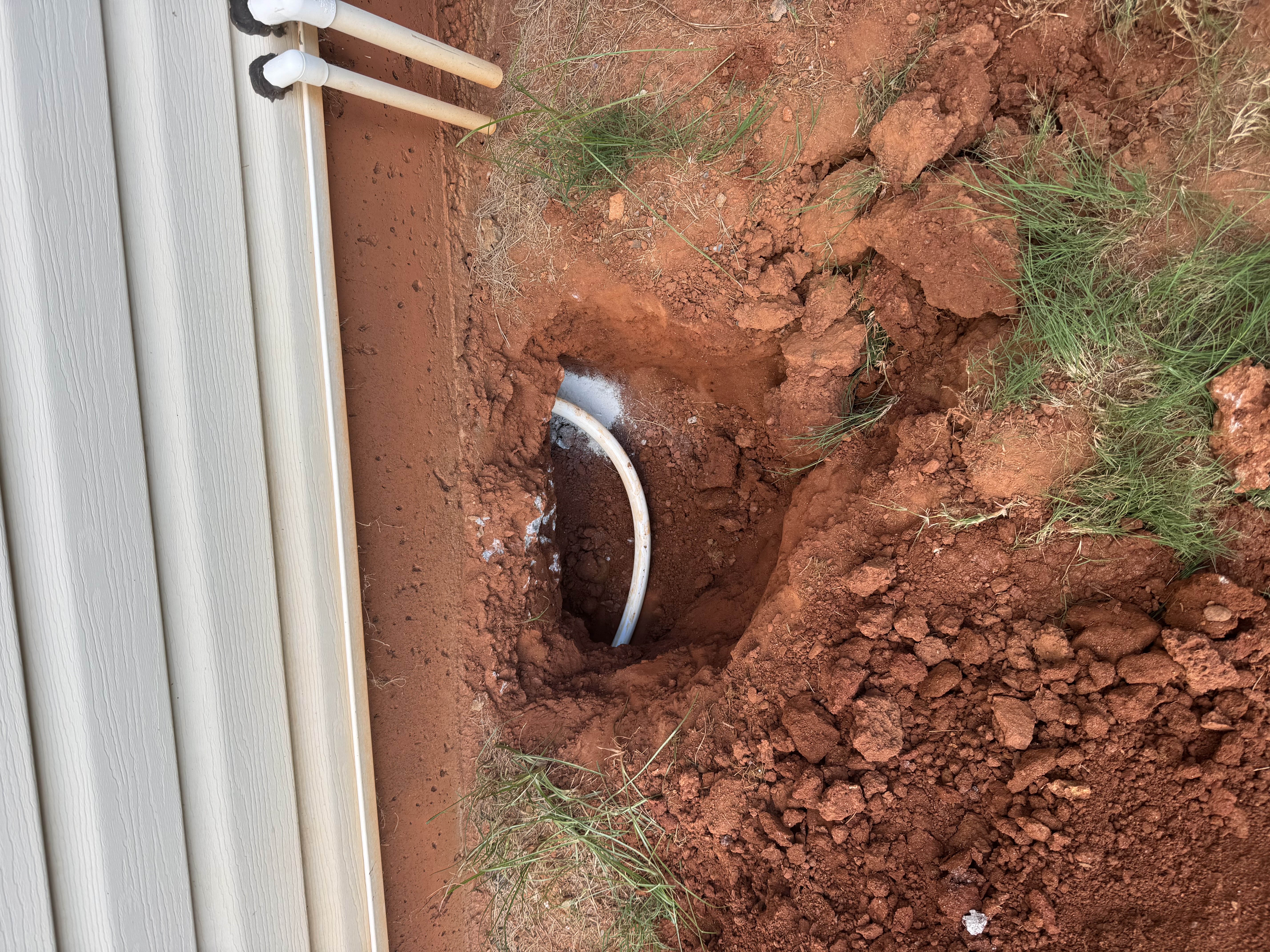 Entry point at the foundation — new water line emerging through the excavation