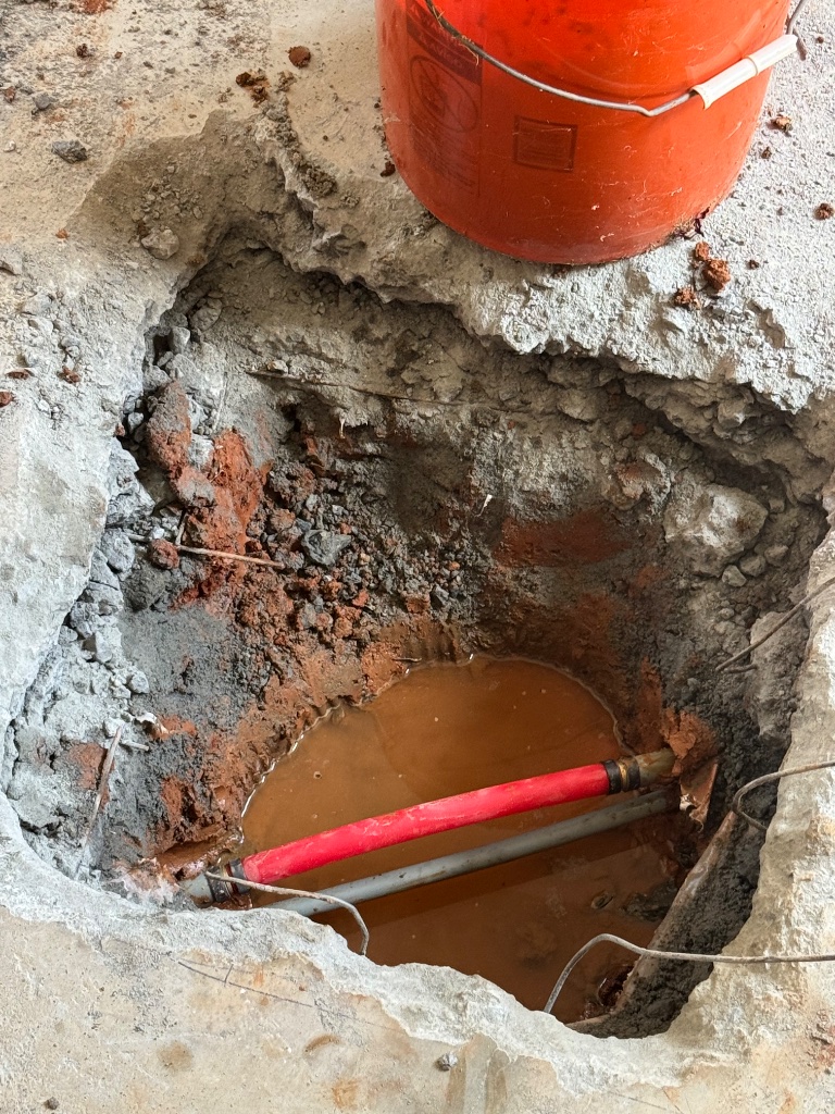 New red PEX pipe installed through the opening