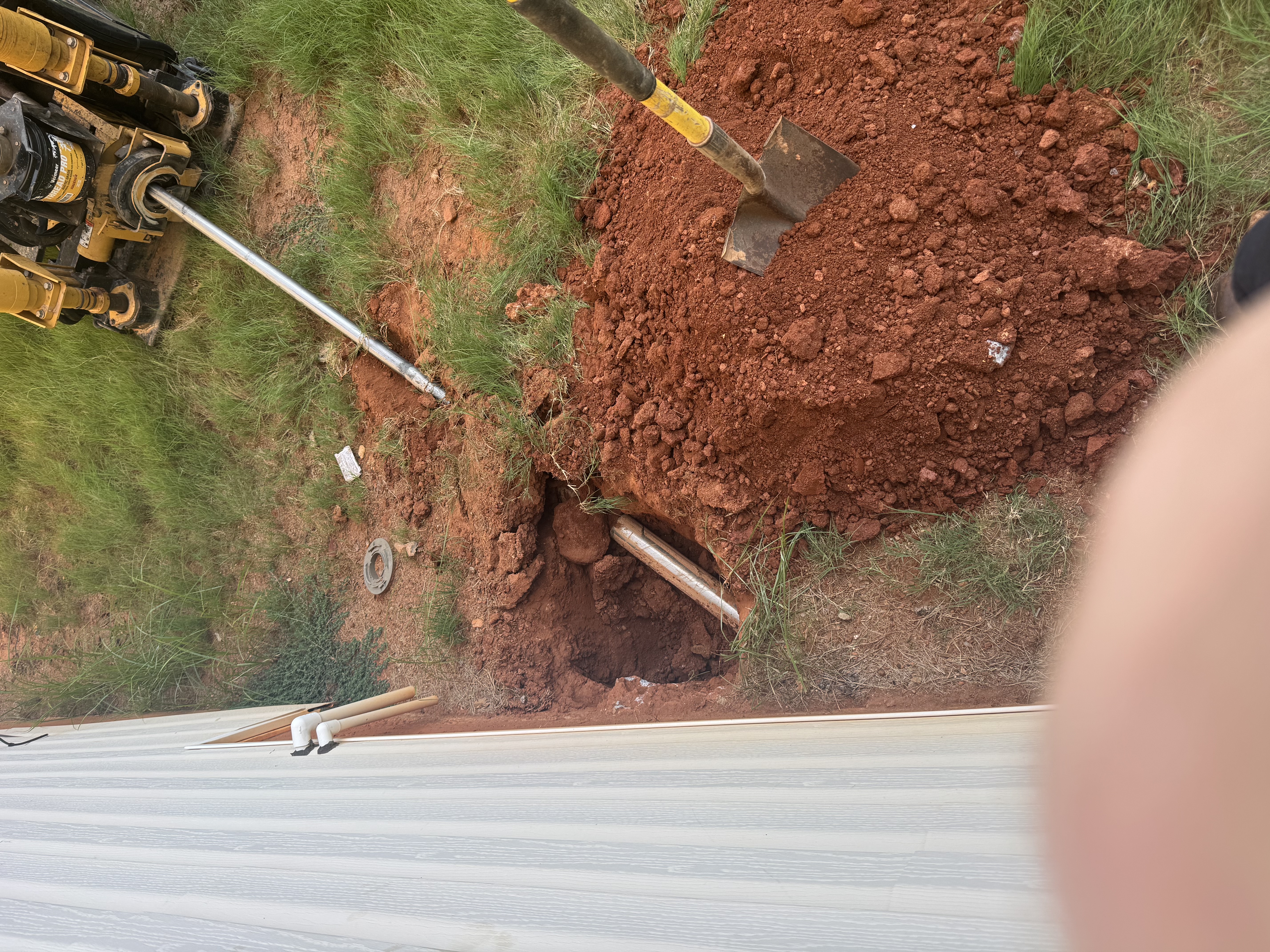 Directional bore in progress — drill rod running underground from the boring machine to the house