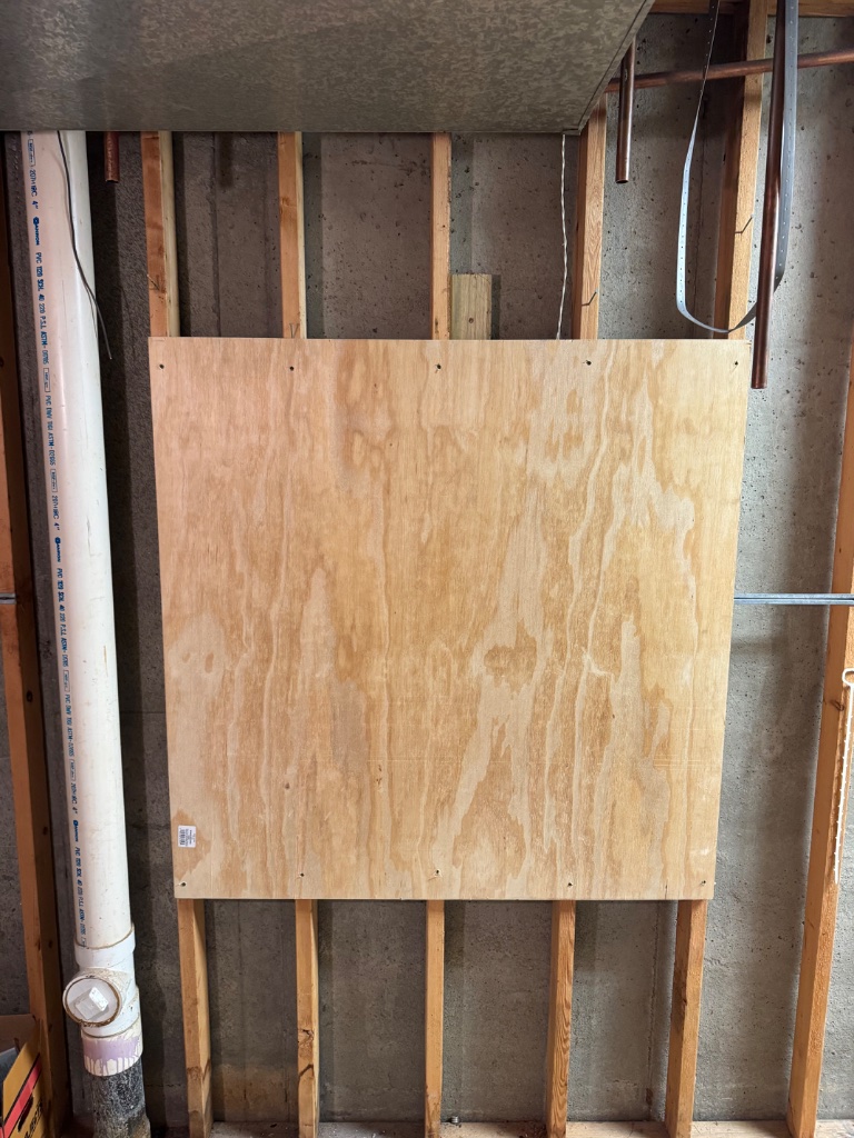 Plywood mounting board installed against the foundation wall
