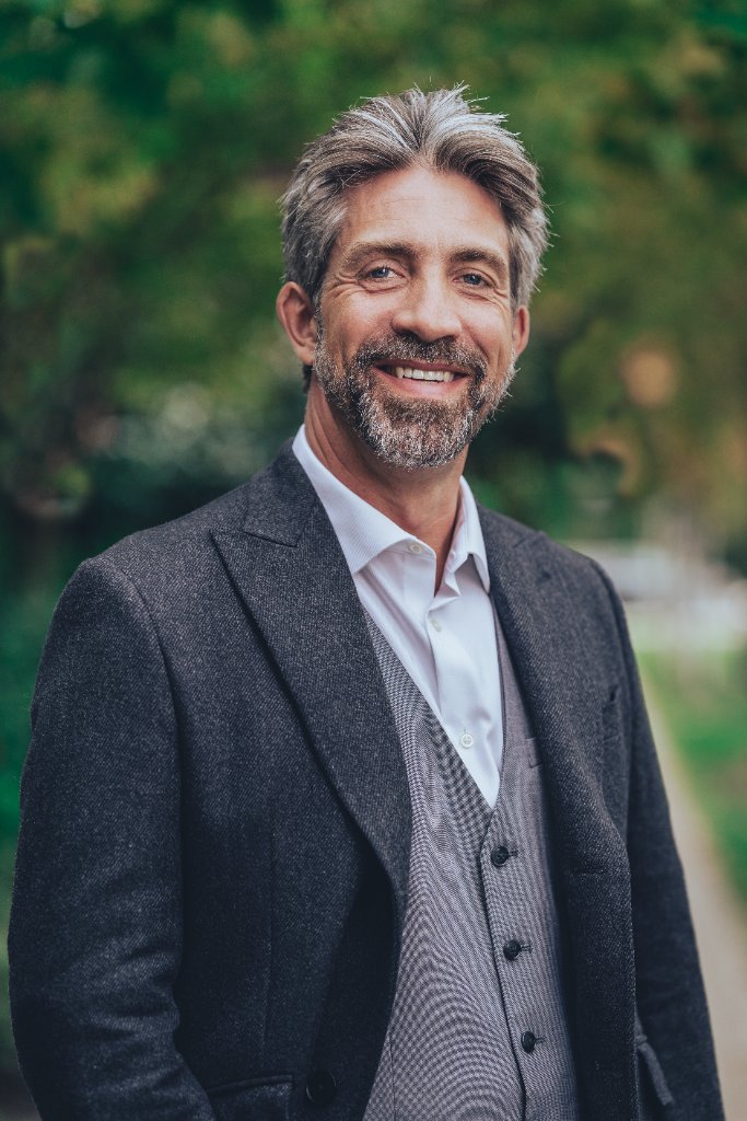 James Burden, a warm and approachable Speech-Language Pathologist, smiling in a natural outdoor setting