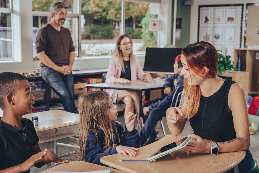A professional working one-on-one with a child in a classroom, illustrating collaborative, practical support