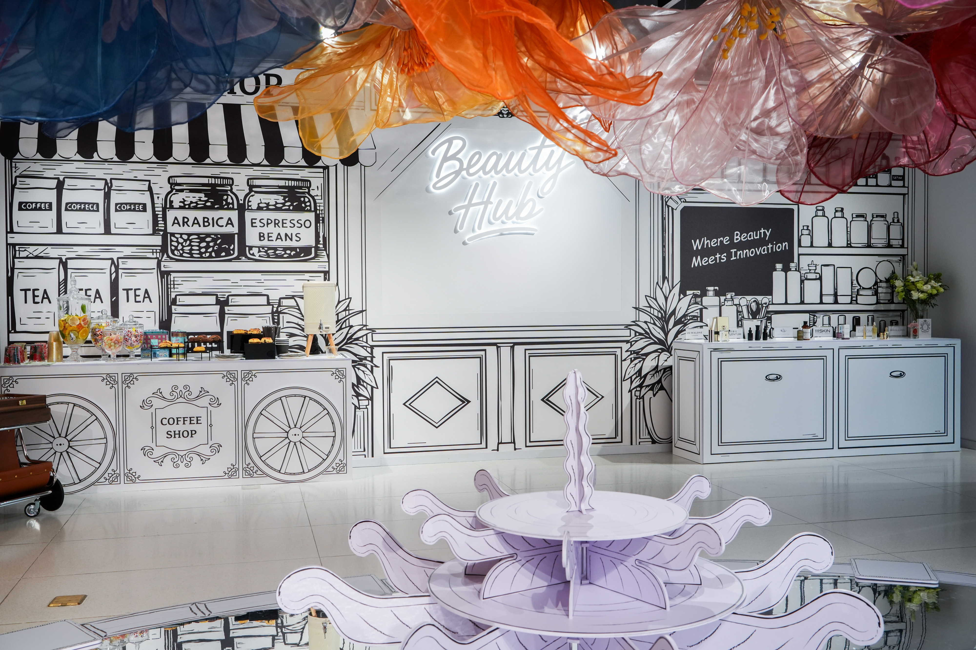 The Beauty Hub set for the forum, its illustrated coffee shop and shelving drawn in line on white.