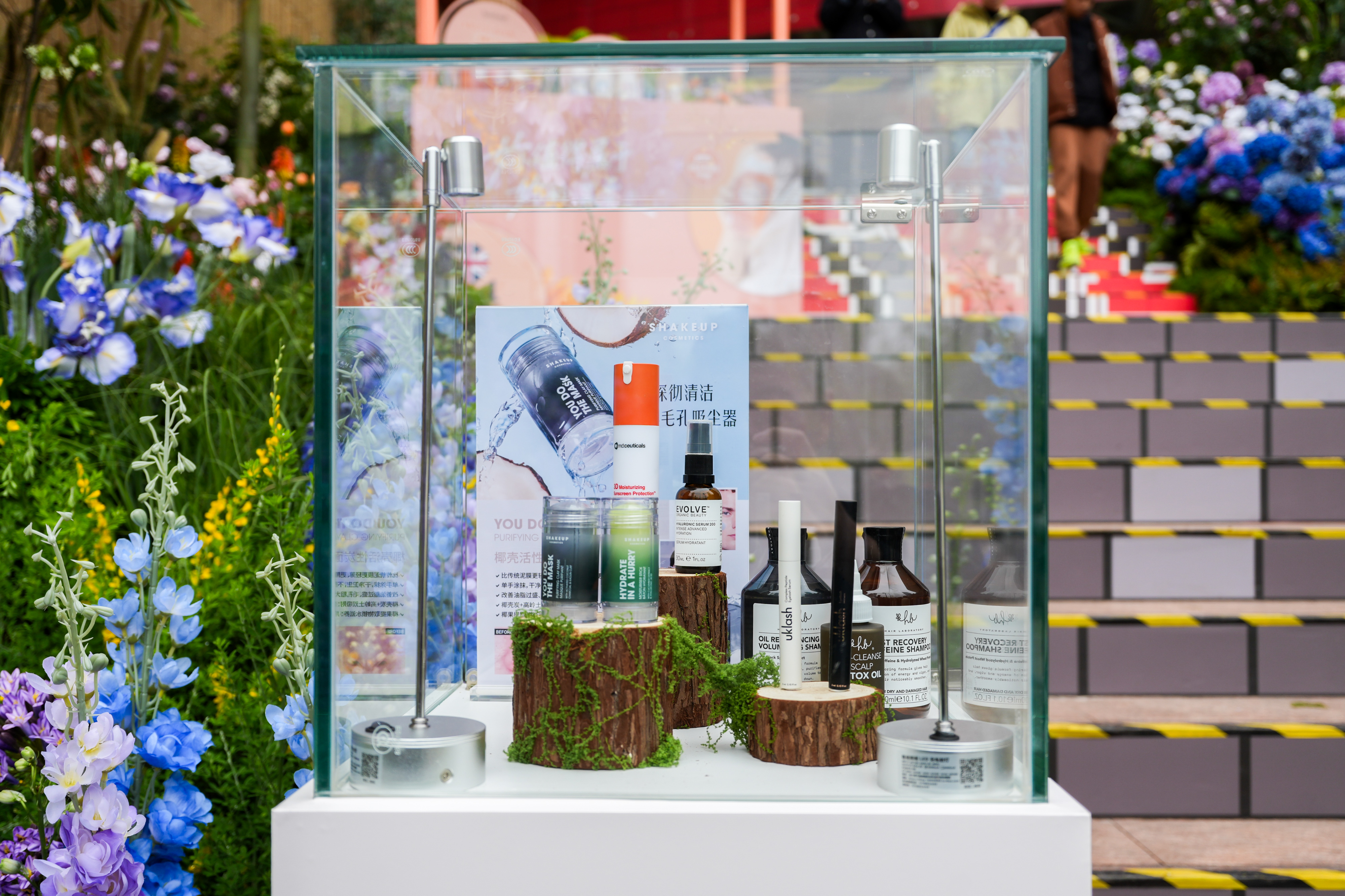 A glass vitrine of hair and skincare set among the planting.