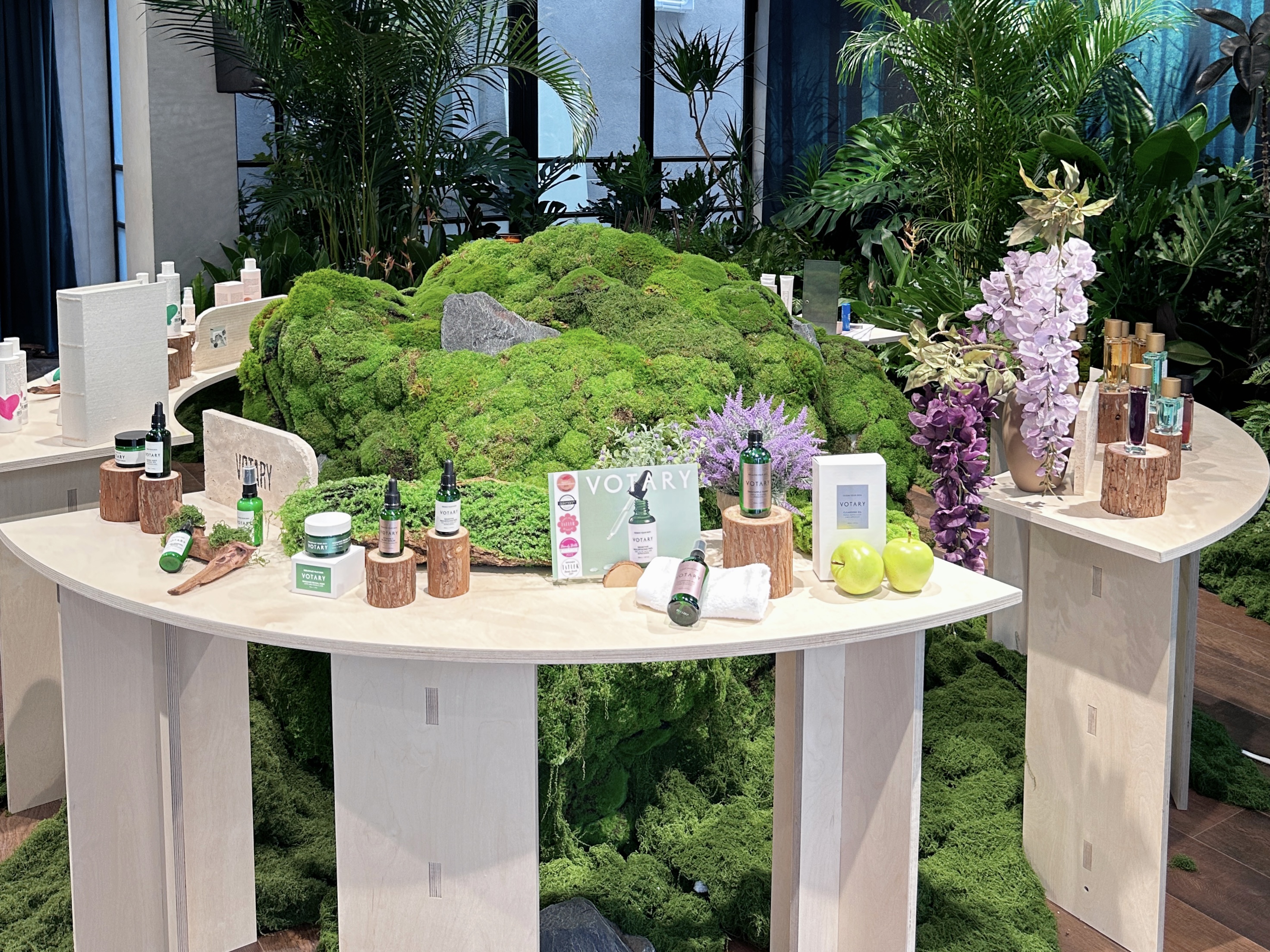 Votary presented on curved plinths beside moss, wisteria and fragrance flacons