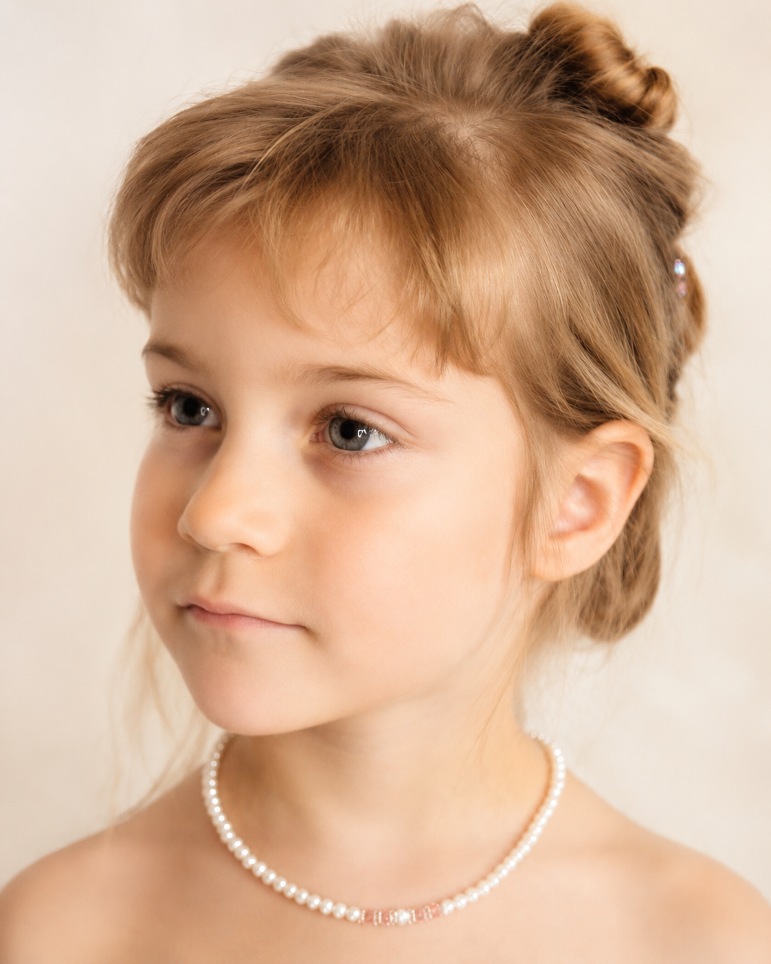 Young girl wearing a delicate pearl necklace with soft crystal accents.
