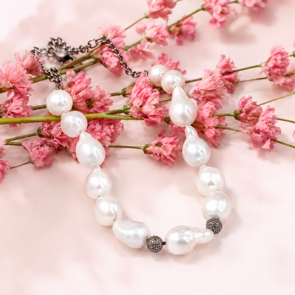 Baroque pearl necklace with pavé accents draped over pink flowers by Jewelry by Candy