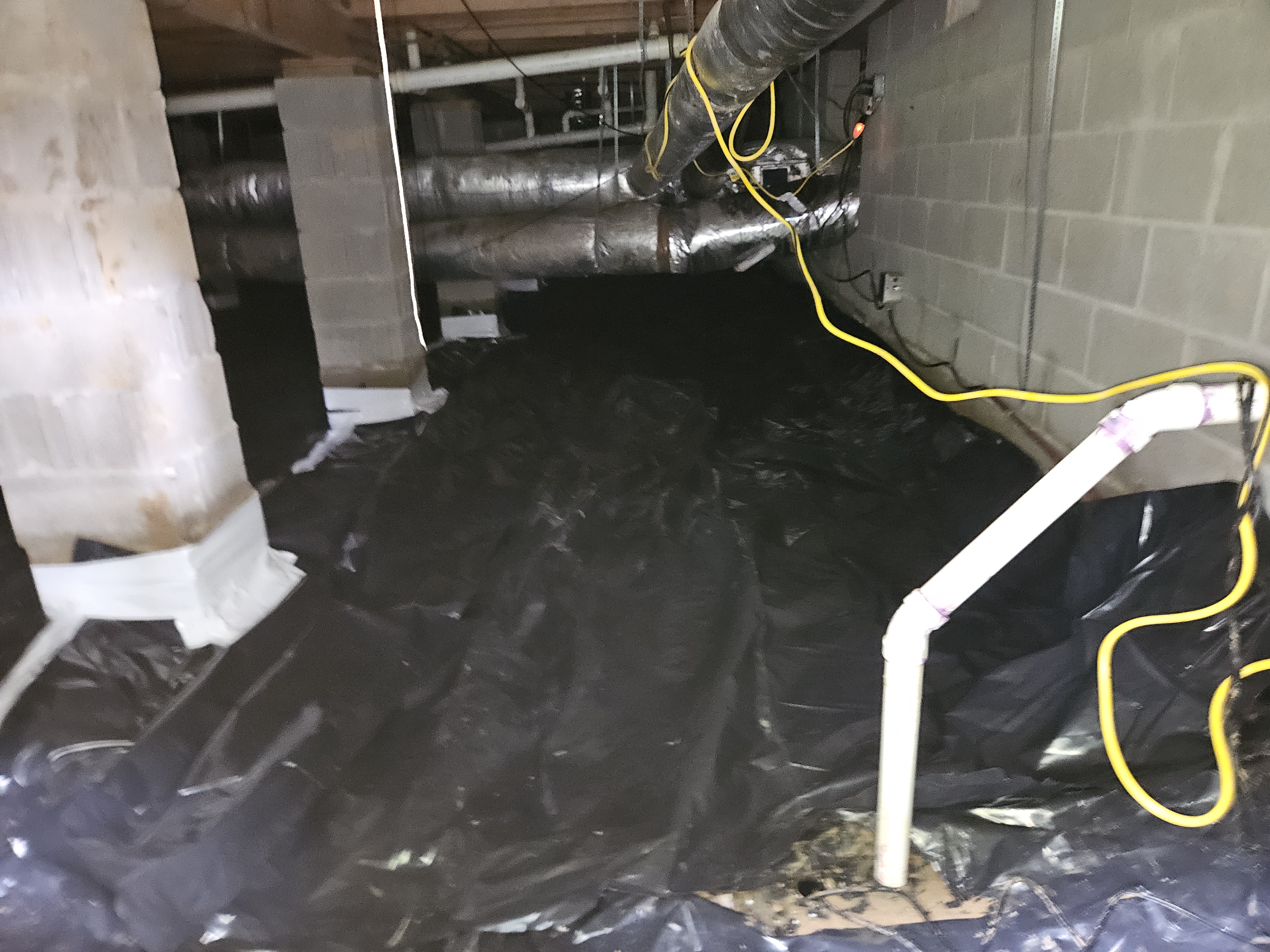 Crawl space drainage and vapor barrier installation in Murfreesboro, TN with a PVC discharge pipe and sealed concrete support piers