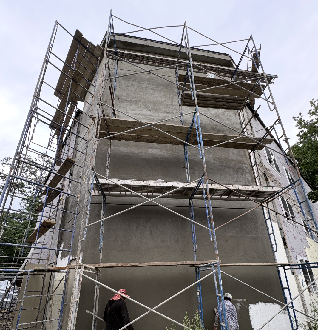 Kiri Construction crew applying stucco to a multi-story building exterior from scaffolding on a DeWitt job in the Bronx, NY