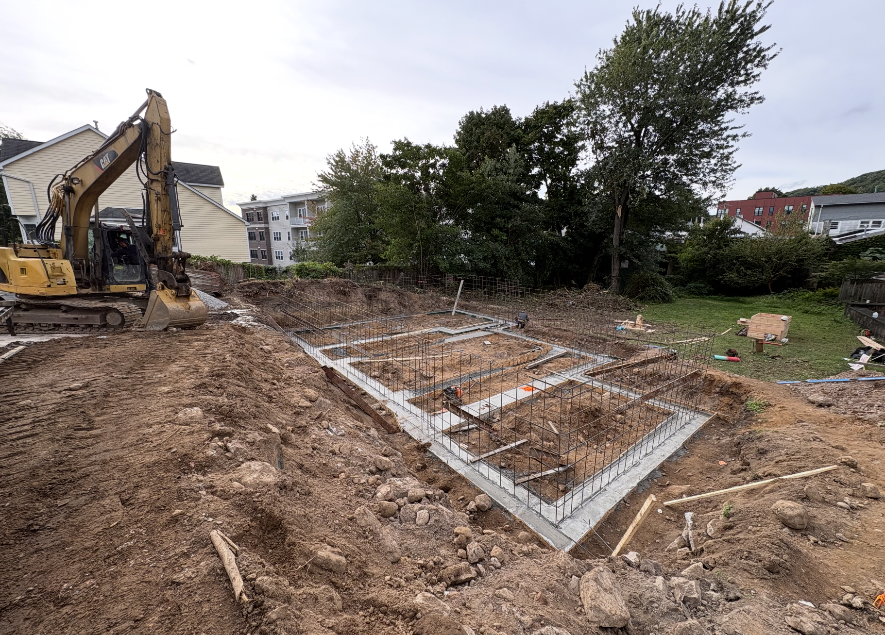 Excavated foundation with poured concrete footings and vertical rebar at the start of a new build in Nyack, NY
