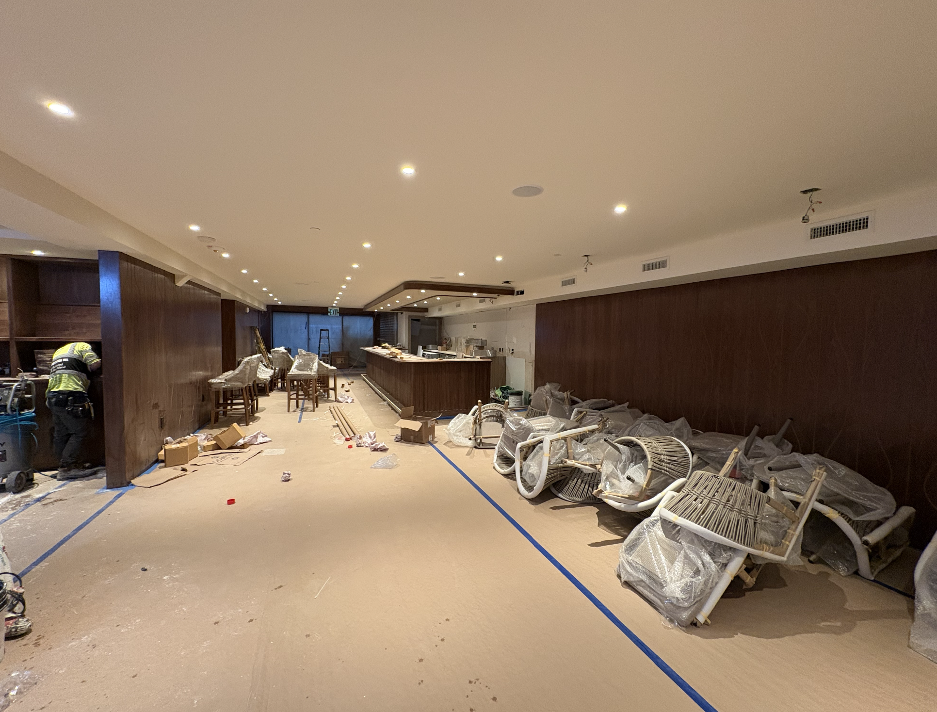 Seafire Grill restaurant interior build-out in progress with walnut wall paneling, a long wood bar, recessed lighting and protected new seating at the Seafire Grill 49th Street location in NYC