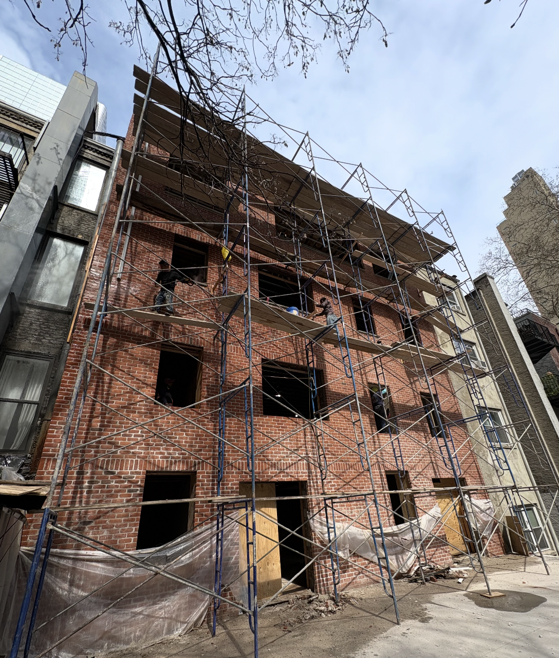 Masons on scaffolding laying new red brick across a four-story rear facade at the Seafire Grill 49th Street location in NYC
