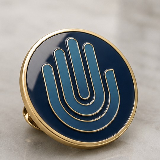 The First Backers' pin — concept render: the raised hand in teal on navy enamel, gold rim