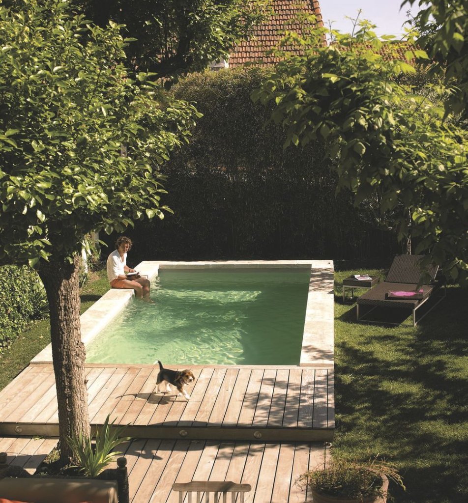 Piscine d'une location de vacances avec voyageur lisant au bord de l'eau