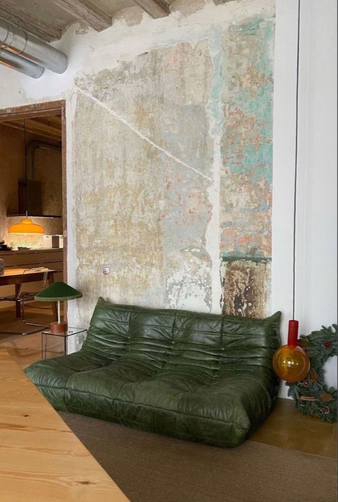 Salon rustico-chic avec canapé en cuir vert patiné dans une location haut de gamme