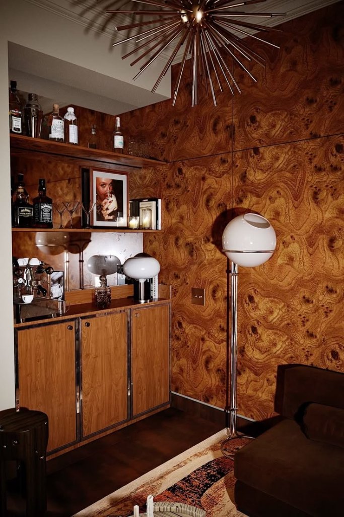 Bar en noyer ronceux verni, lampe globe et lustre étoile dans un intérieur raffiné aux textures chaleureuses