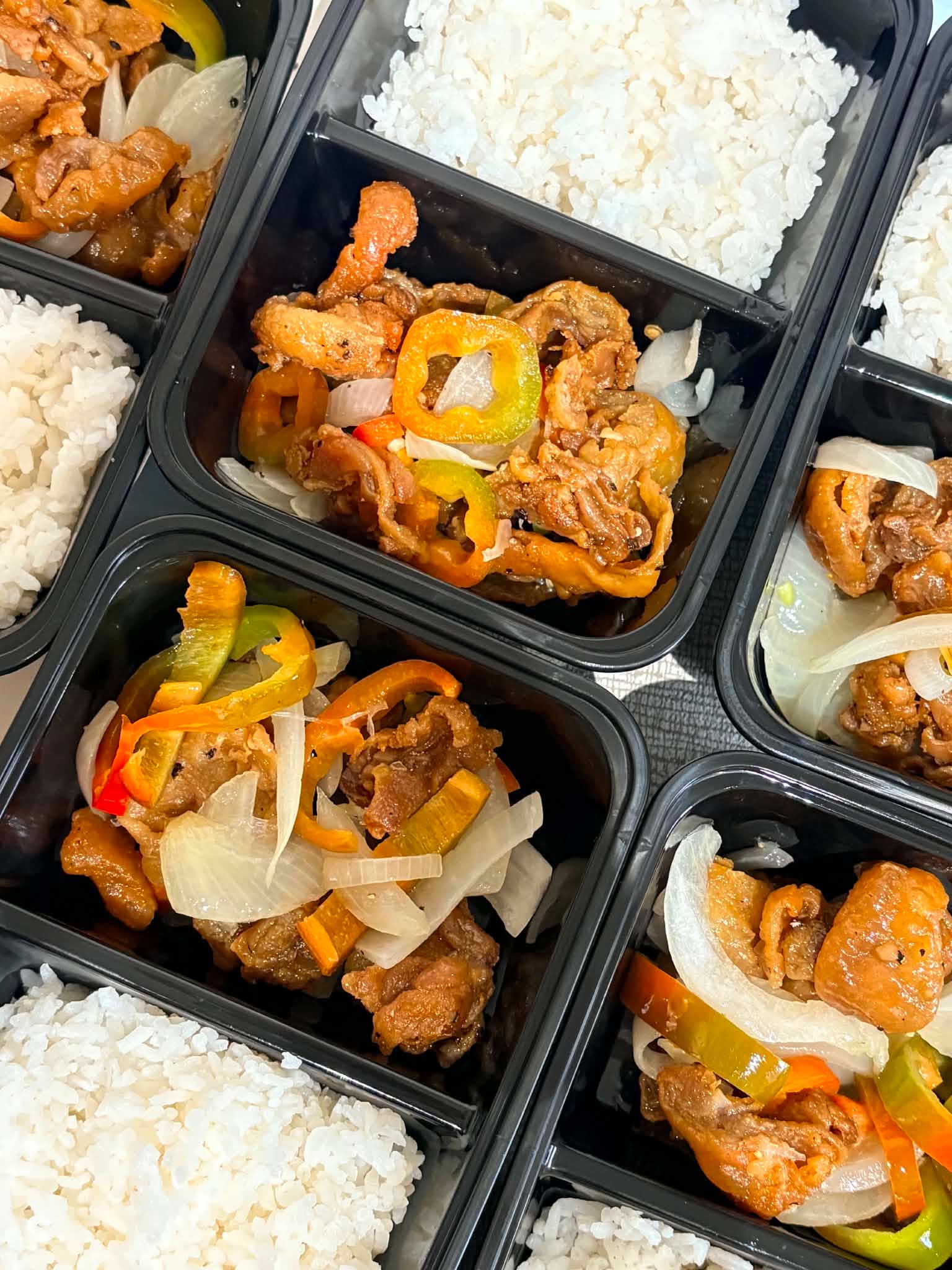 Bulk meal-kit spread of Filipino crew meals in portioned containers
