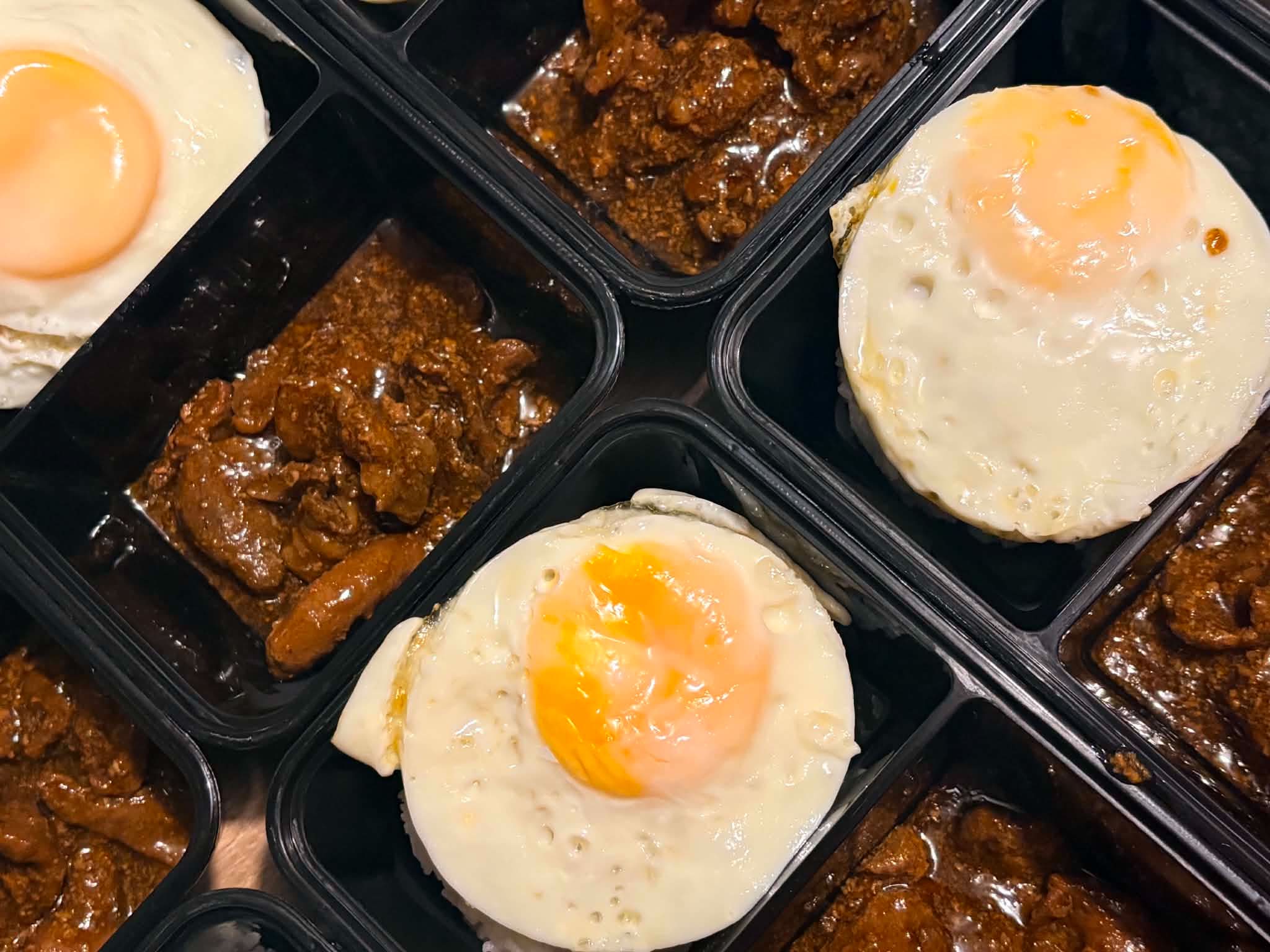Bulk meal-kit spread of Filipino crew meals in portioned containers