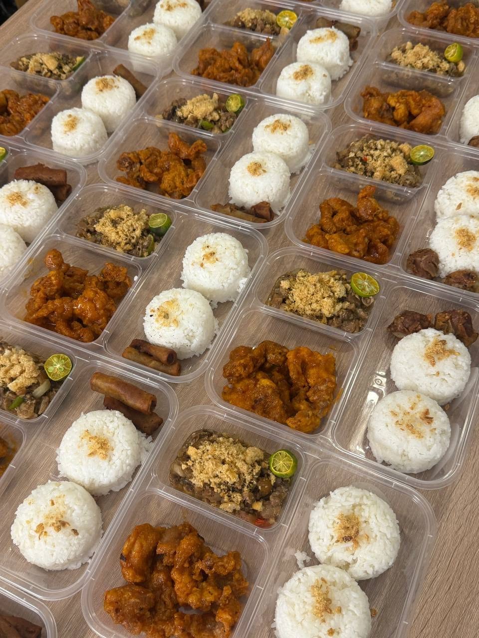 Bulk meal-kit spread of Filipino crew meals in portioned containers