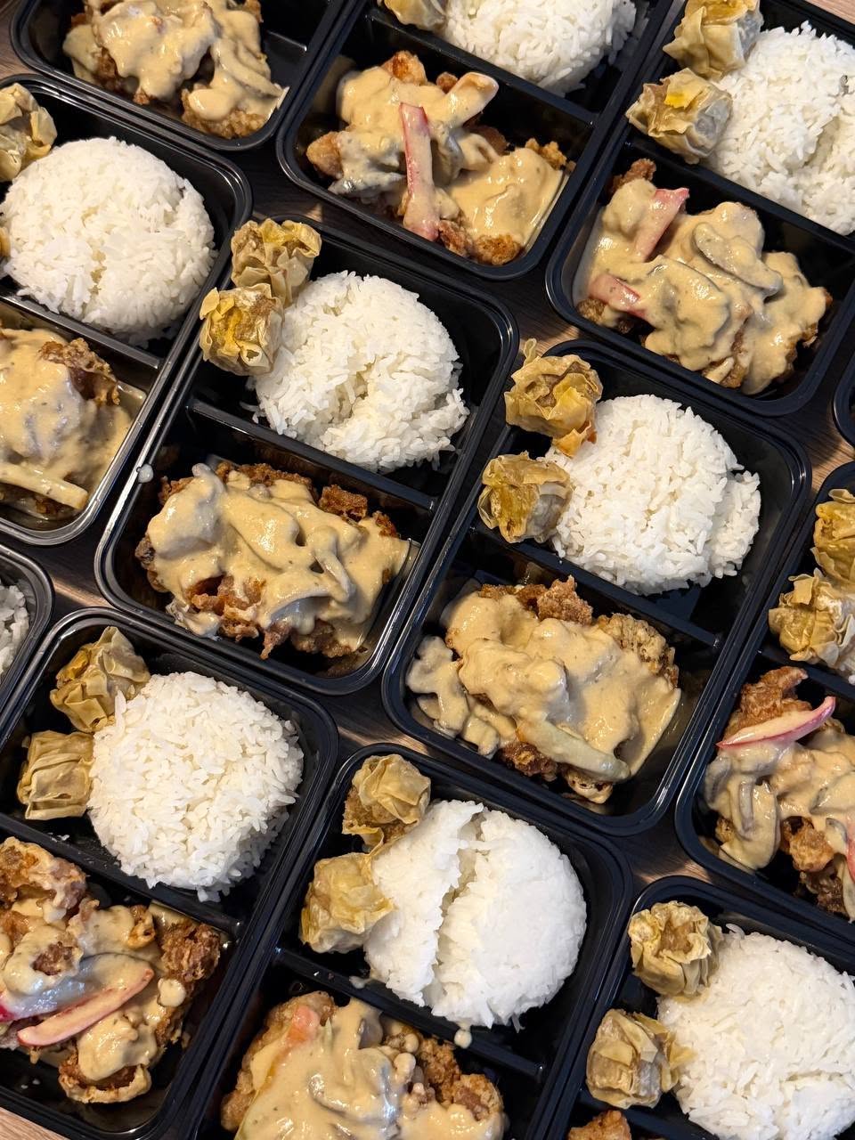 Bulk meal-kit spread of Filipino crew meals in portioned containers