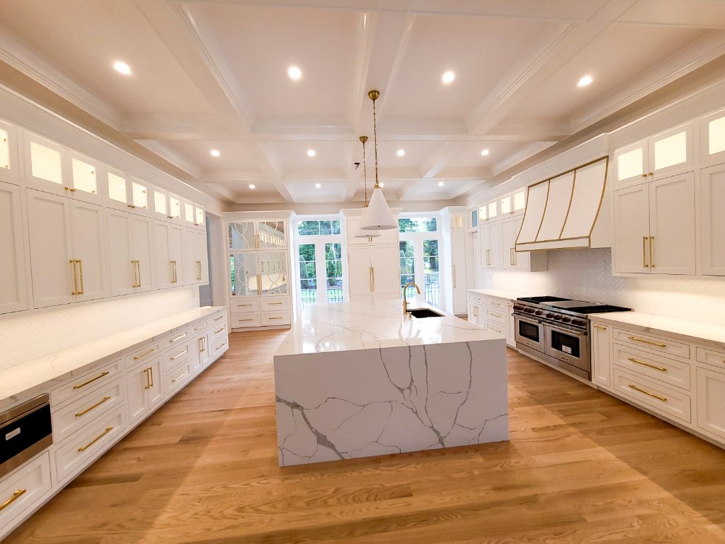 Luxury white kitchen cabinetry with gold hardware and marble island