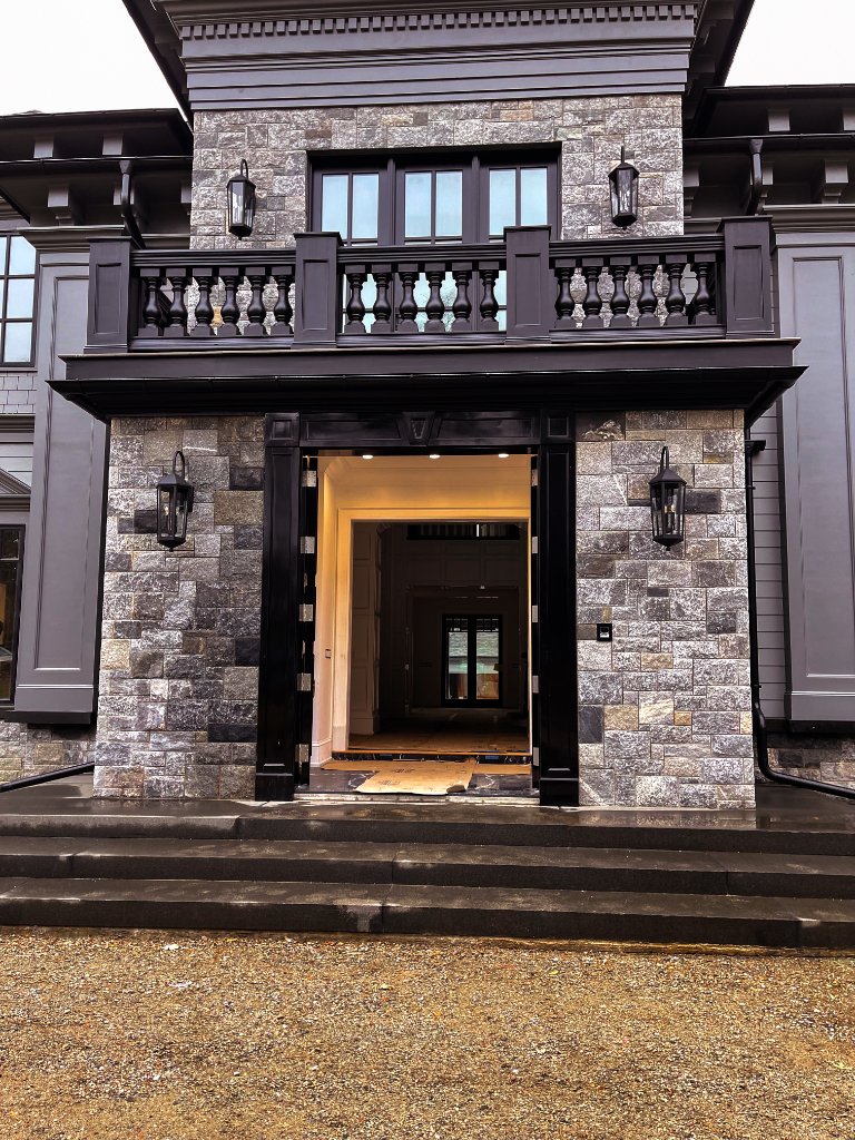 Grand entrance with hand-carved wood balcony railing and stone facade