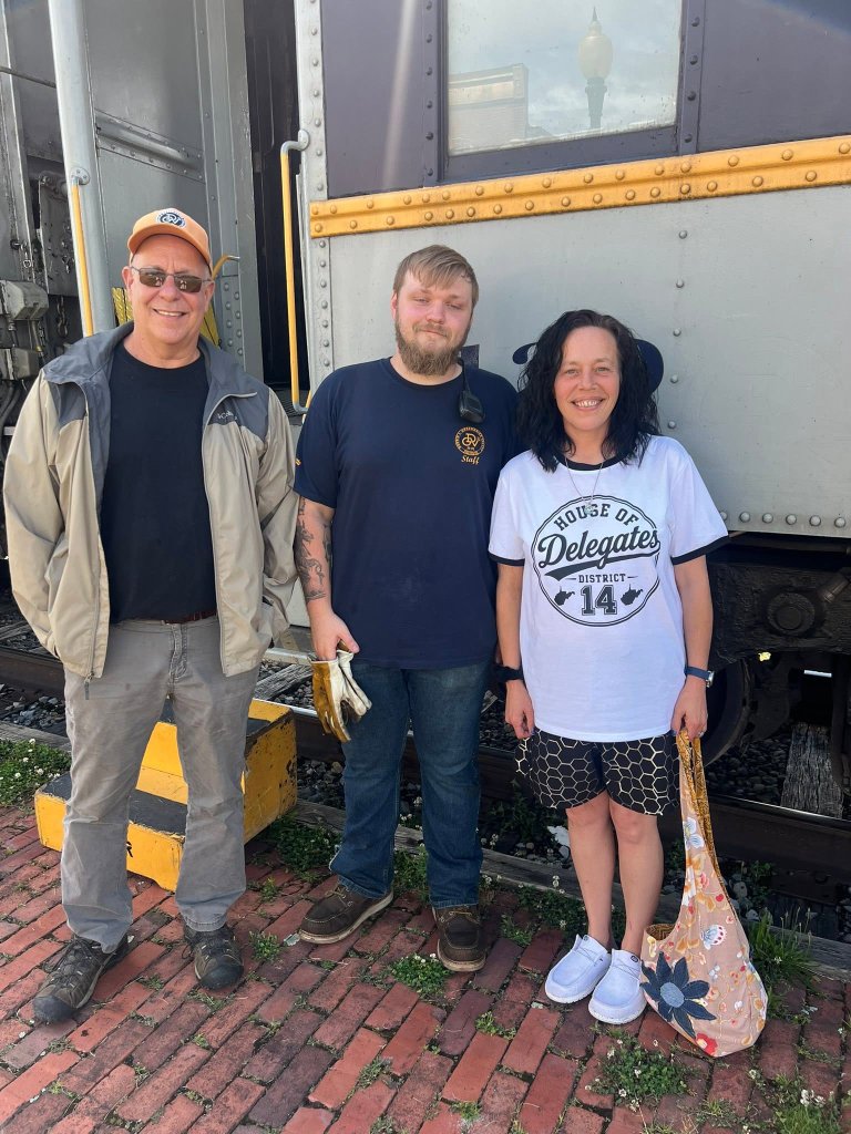 Crystal Butcher standing with supporters and campaign staff in front of a train car, proudly wearing her House of Delegates District 14 shirt