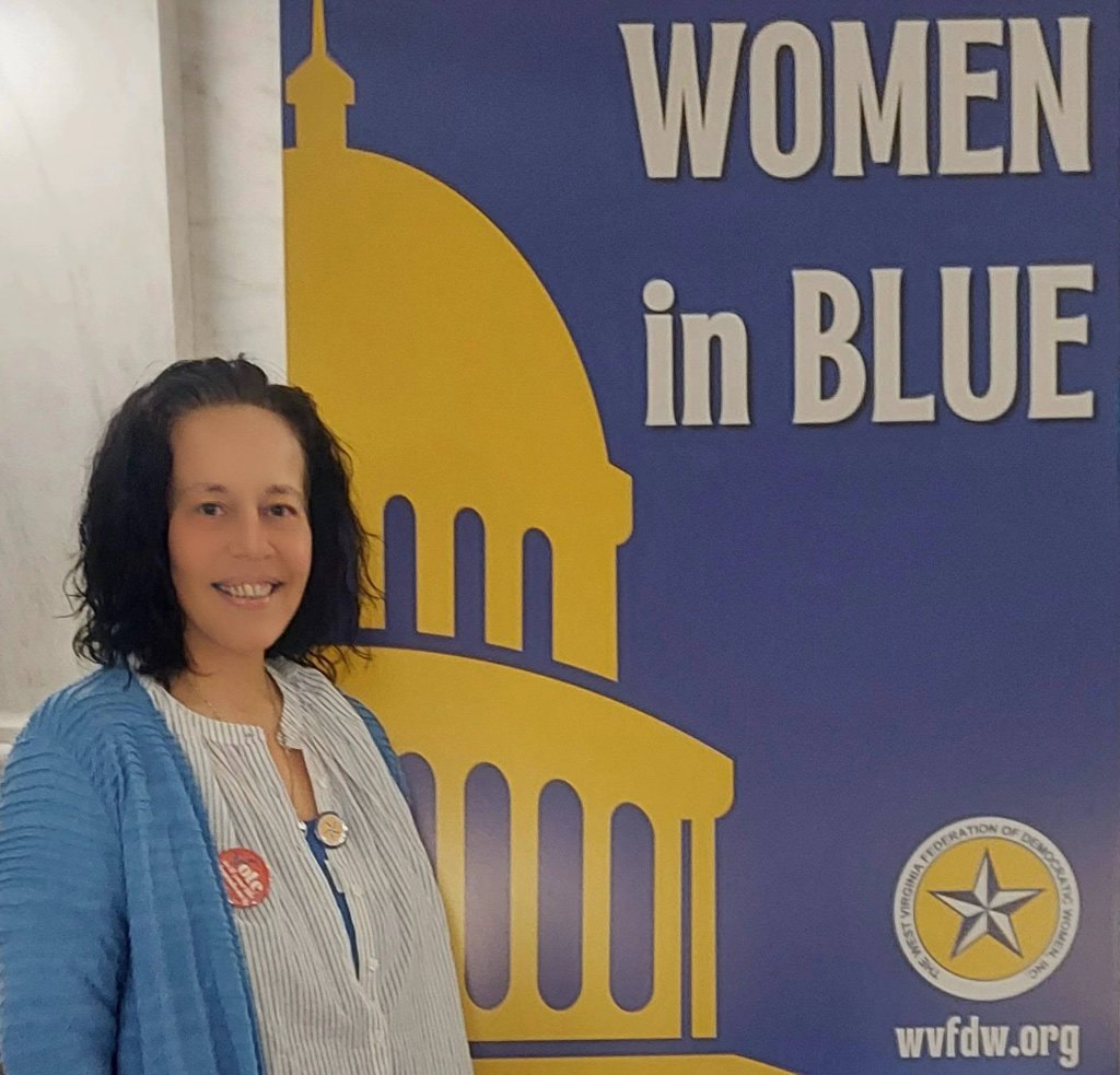 Crystal Butcher standing beside a Women in Blue banner at the West Virginia Federation of Democratic Women event