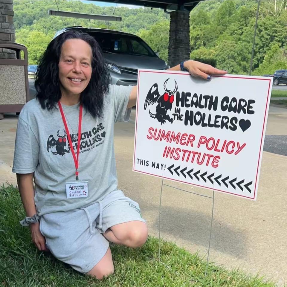 Crystal Butcher at the Health Care in the Hollers Summer Policy Institute holding a directional sign