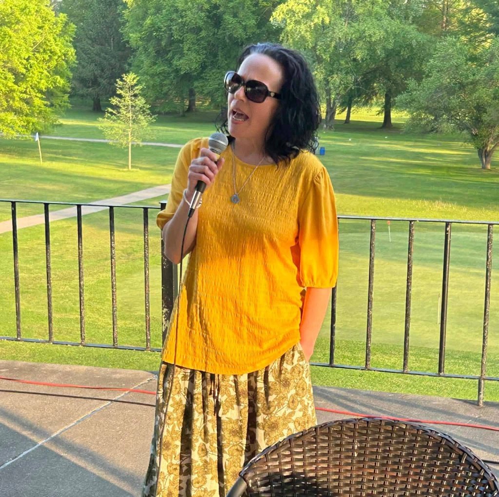 Crystal Butcher speaking into a microphone at a community gathering, engaging with District 14 residents