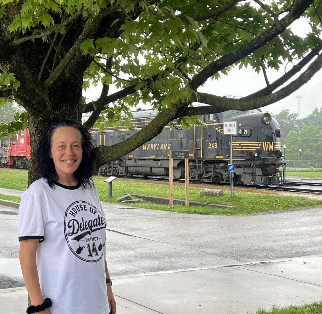 Crystal Butcher wearing her House of Delegates District 14 shirt standing in front of a vintage locomotive